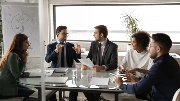 Geschäftsleute diskutieren am Konferenztisch strategische Themen, intensive Zusammenarbeit und professionelle Beratung im Bereich Consulting.