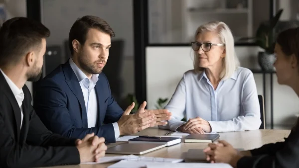 Geschäftsleute diskutieren am Konferenztisch strategische Themen, intensive Zusammenarbeit und professionelle Beratung im Bereich Consulting.