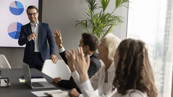 Team im Meeting diskutiert aktiv mit Berater vor Präsentation, gemeinsame Analyse und Lösungsfindung im Consulting.