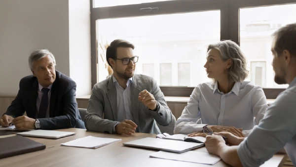 Führungskraft diskutiert mit Team am Konferenztisch, intensiver Austausch im Büro, Leadership und strategische Zusammenarbeit im Fokus.