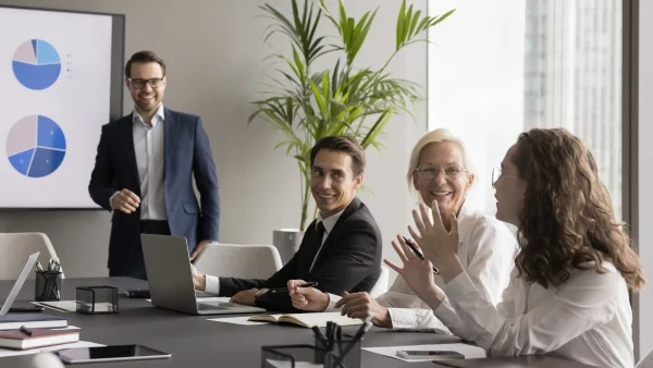 Teilnehmer diskutieren im Meeting mit Trainer, lebendige Gruppenarbeit und praxisnahe Inhalte während professioneller Sales Trainings.