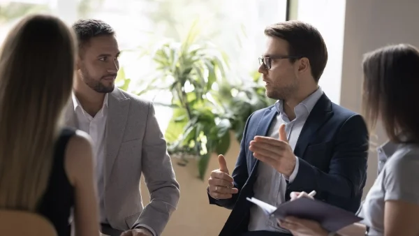 Trainer erklärt Verkaufstechniken im Gespräch mit Teilnehmern, praxisnaher Austausch und Coaching während intensiver Sales Trainings.