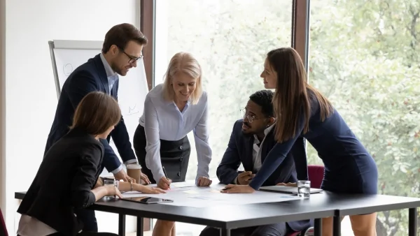 Gruppe arbeitet gemeinsam am Tisch, intensiver Austausch und Teamcoaching im Rahmen von Seminare Persönlichkeitsentwicklung.