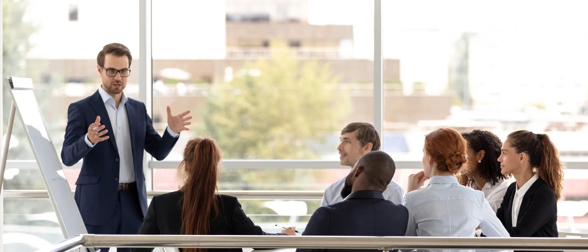 Berater präsentiert am Flipchart vor Team im Konferenzraum, gemeinsame Strategieplanung und Weiterbildung bei Lessig Consulting.